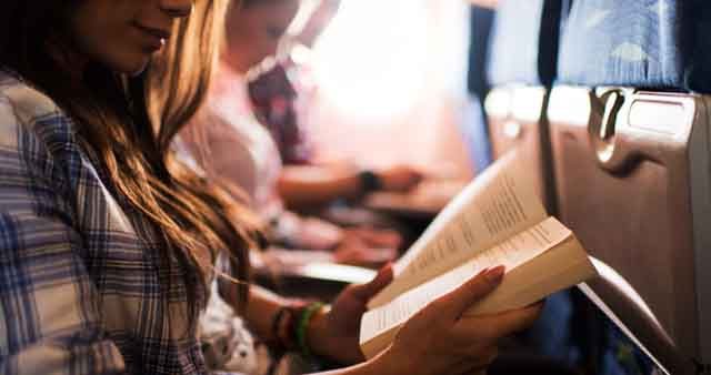 Reading a book while travelling by airplane.
